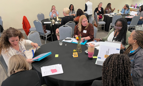 Mentors and mentees sit at tables together discussing how mentors can support NBCT candidates